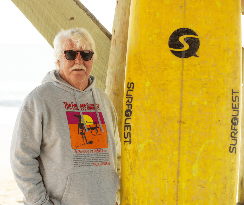 Robert Parker standing with Surfquest surfboard